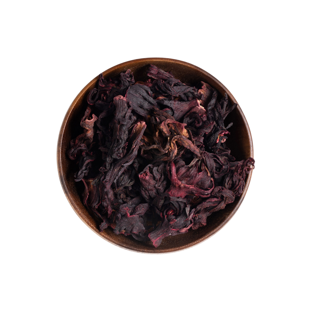Dried dark red and purple hibiscus flowers piled in a round brown ceramic bowl, photographed from above on a plain white background.