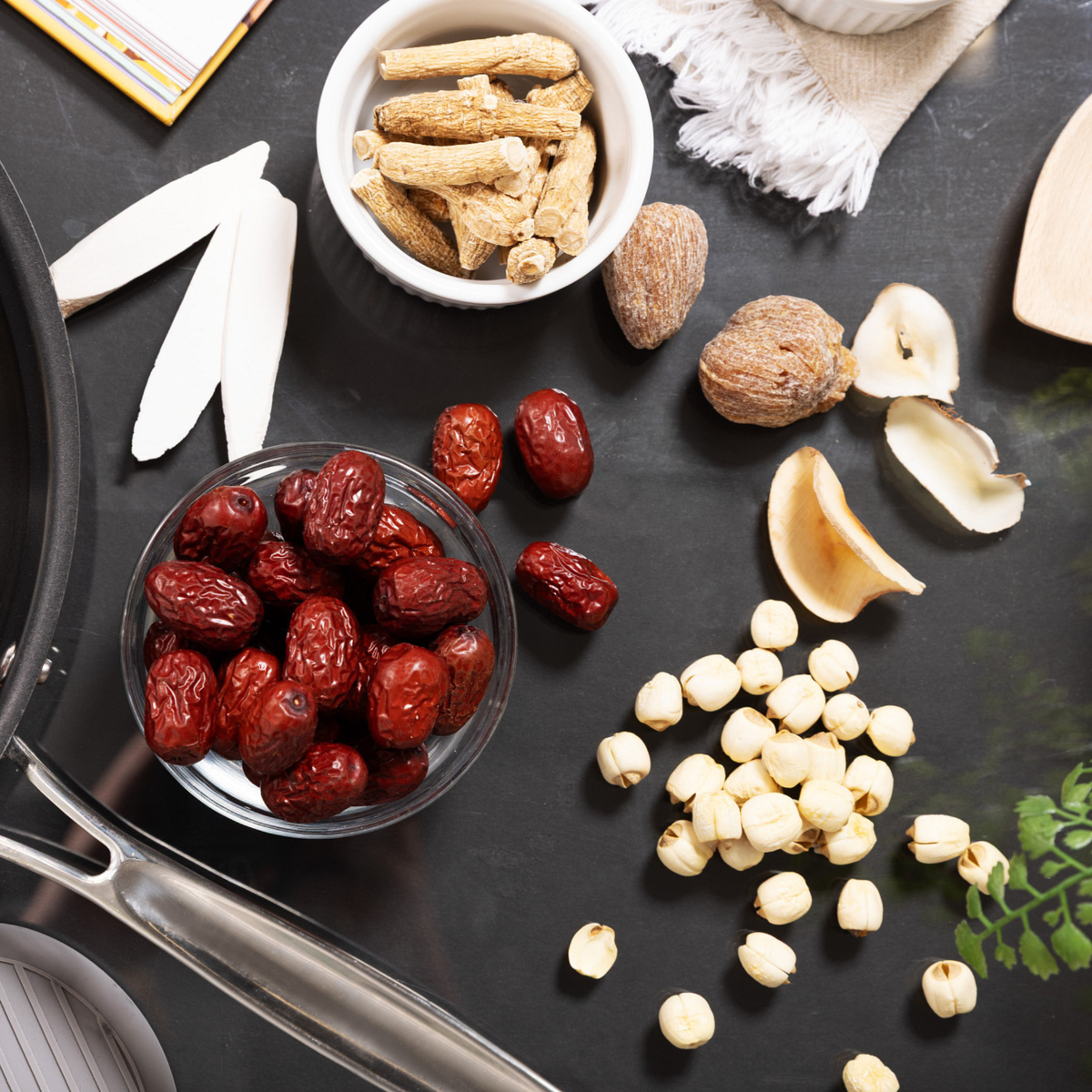 A styled flat-lay of dried and fresh herbal ingredients on a dark surface.