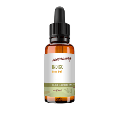A 1 oz amber glass dropper bottle of Root+Spring Tincture of the Month, Indigo, with a white label and black dropper cap, isolated on a white background.